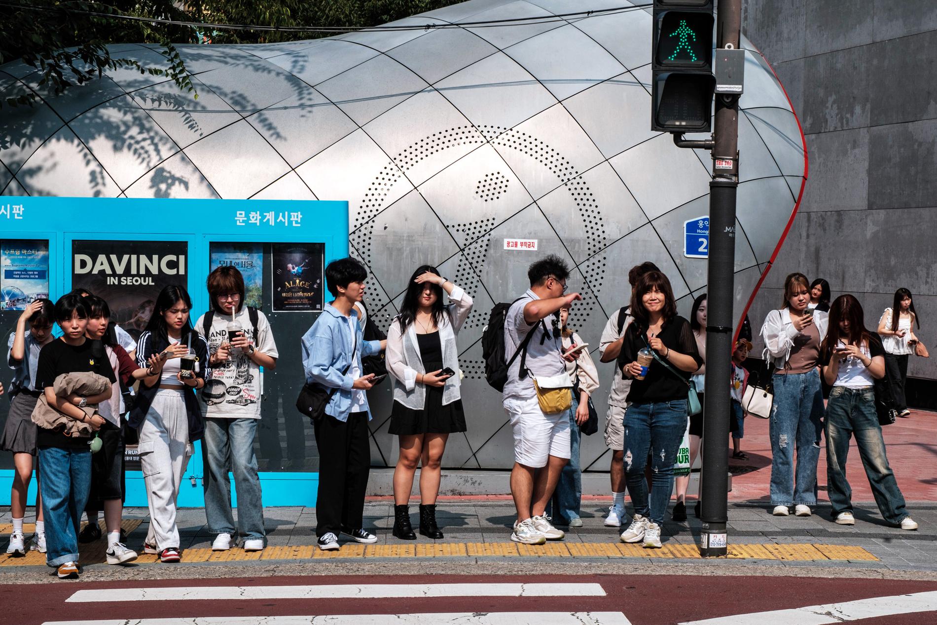 Young people wait at a crosswalk in Seoul's trendy Hongdae district.