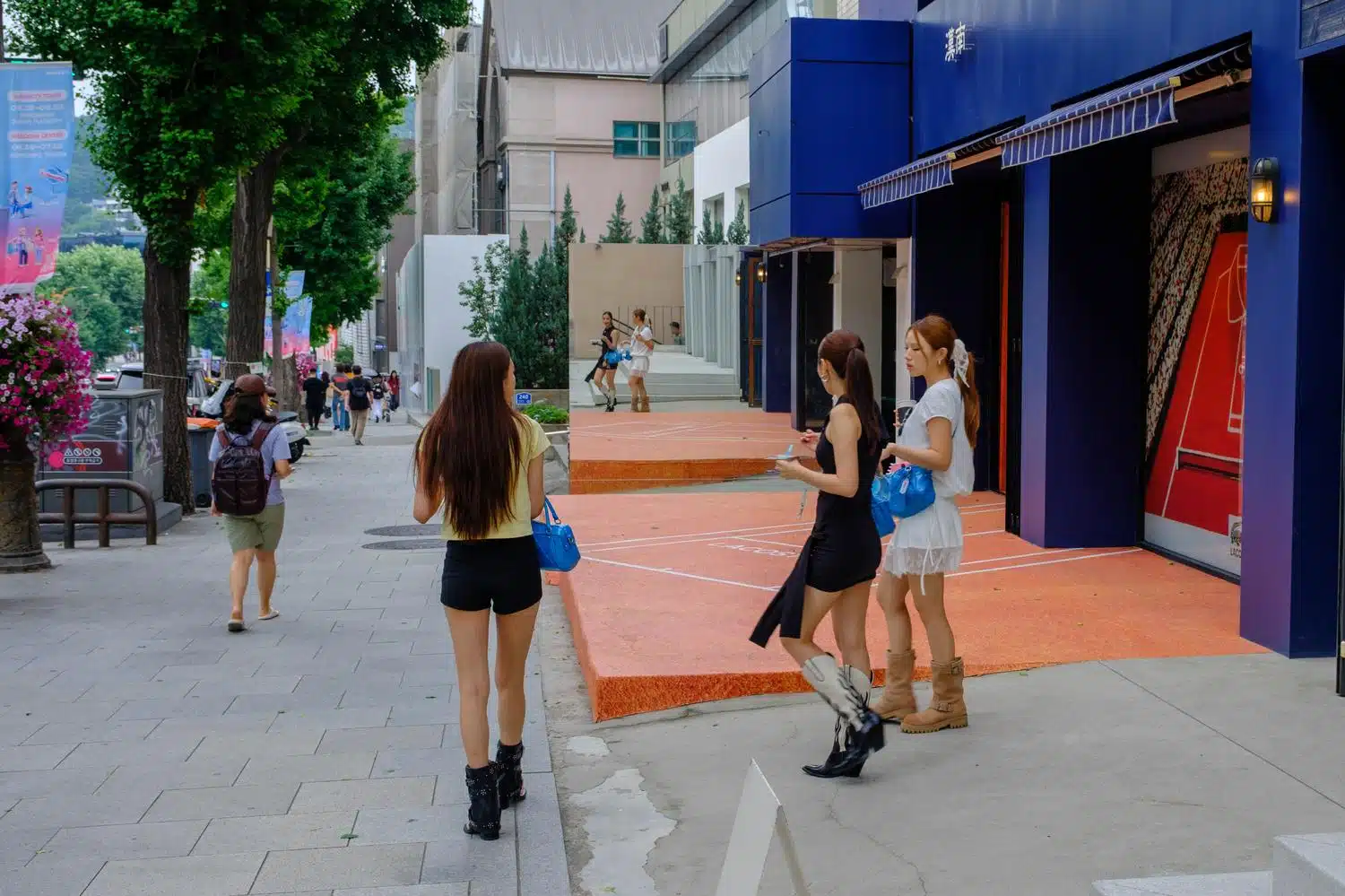 Three young ladies in trendy summer outfits exit a luxury shop in Itaewon
