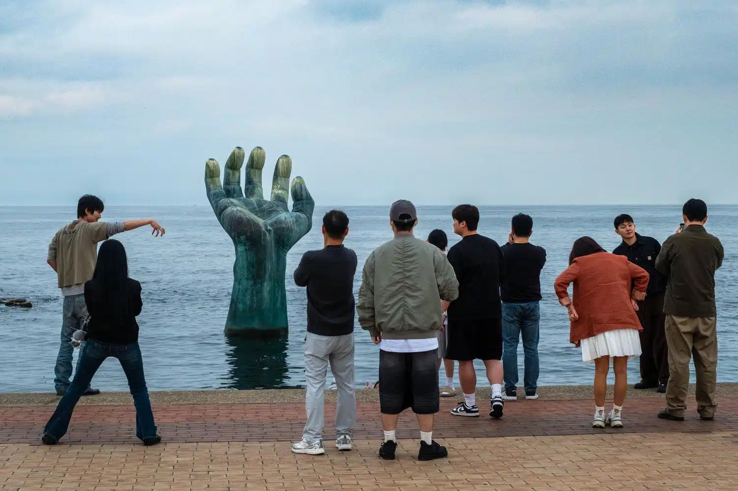 homigot-sunrise-park-hand-korea People take pictures of Sangsaeng’s Hand, a sculpture in the sea in Homigot Sunrise Park, South Korea.
