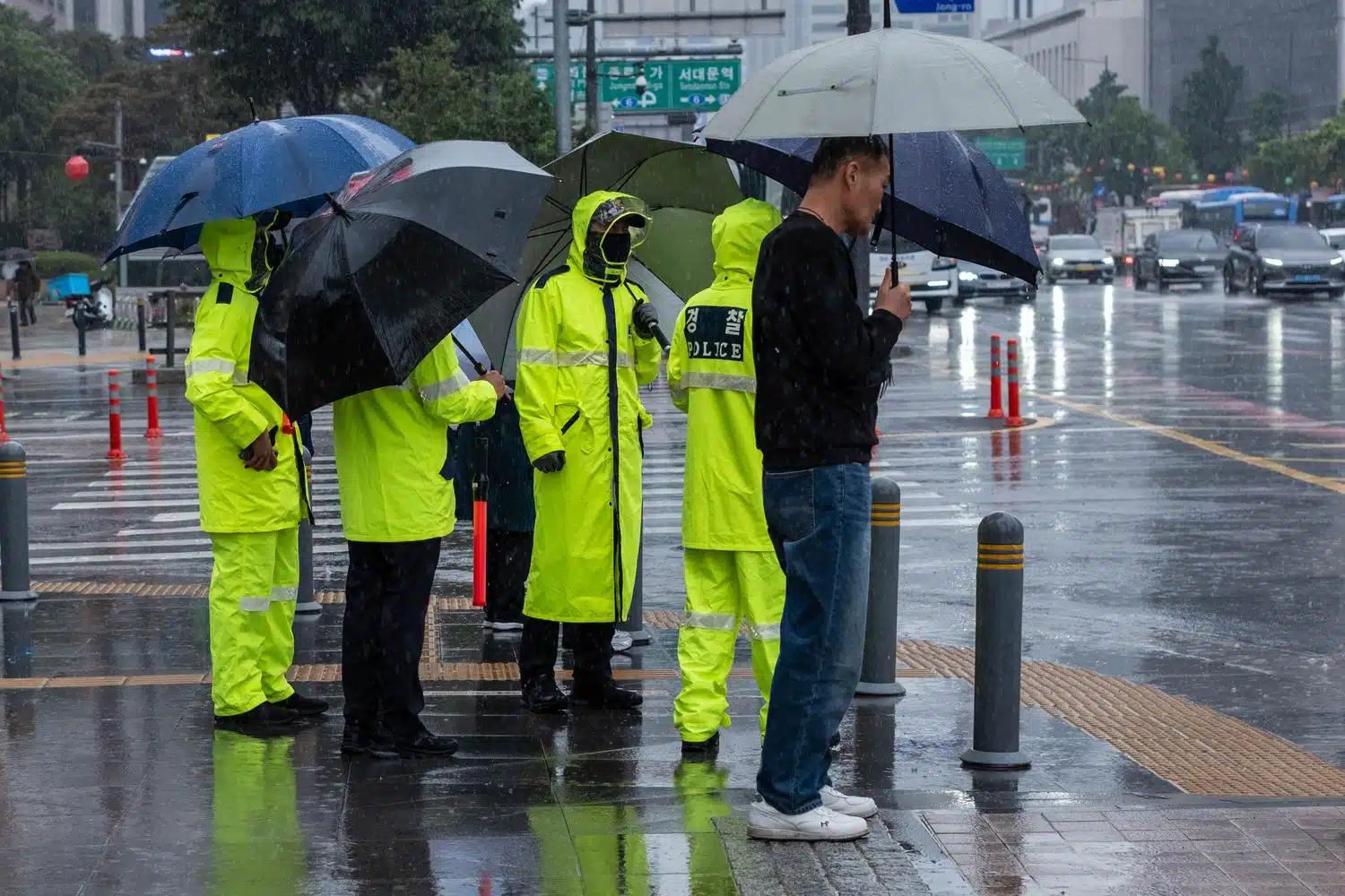 seoul-gwanghwamun-rain-1 Korean policemen wear fluorescent yellow raincoats and carry umbrellas during a rainy day on Seoul's Gwanghwamun square.