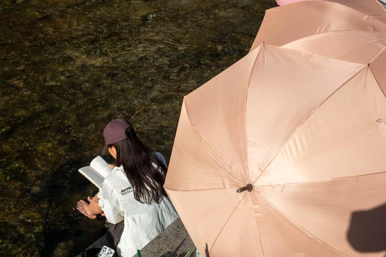 seoul-outdoor-library-summer-2026-16 A woman reads with her feet in the Cheonggyecheon Stream in Seoul