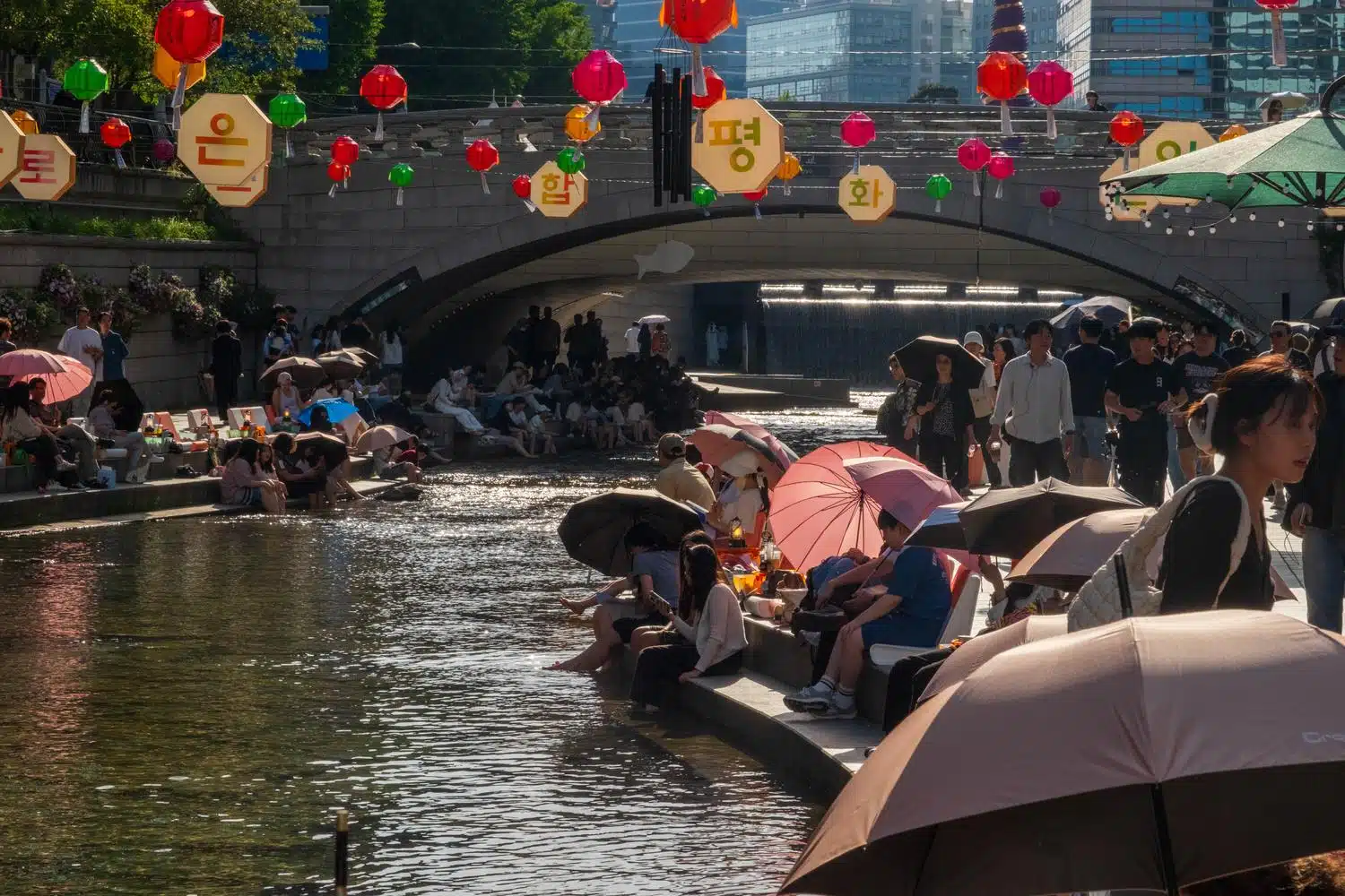 seoul-outdoor-library-summer-2026-19 People relax along Cheonggyecheon stream in central Seoul during the weekend