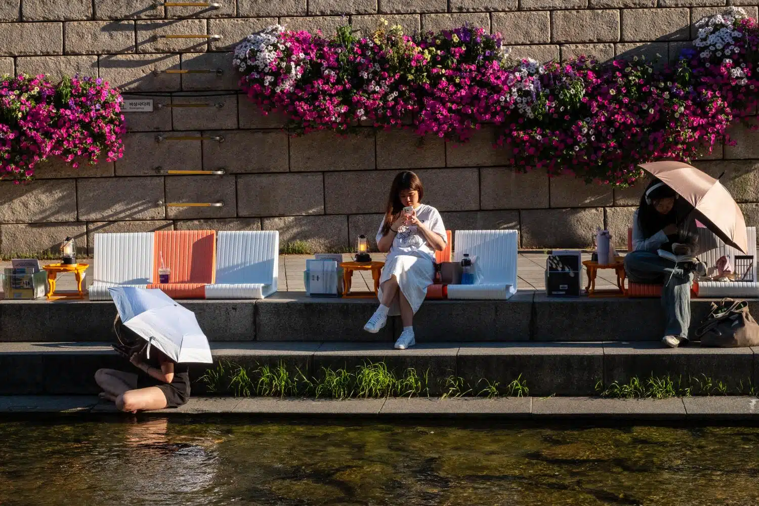 cheonggyecheon-stream-seoul-summer-june-2026 People relax along Cheonggyecheon stream in Seoul.