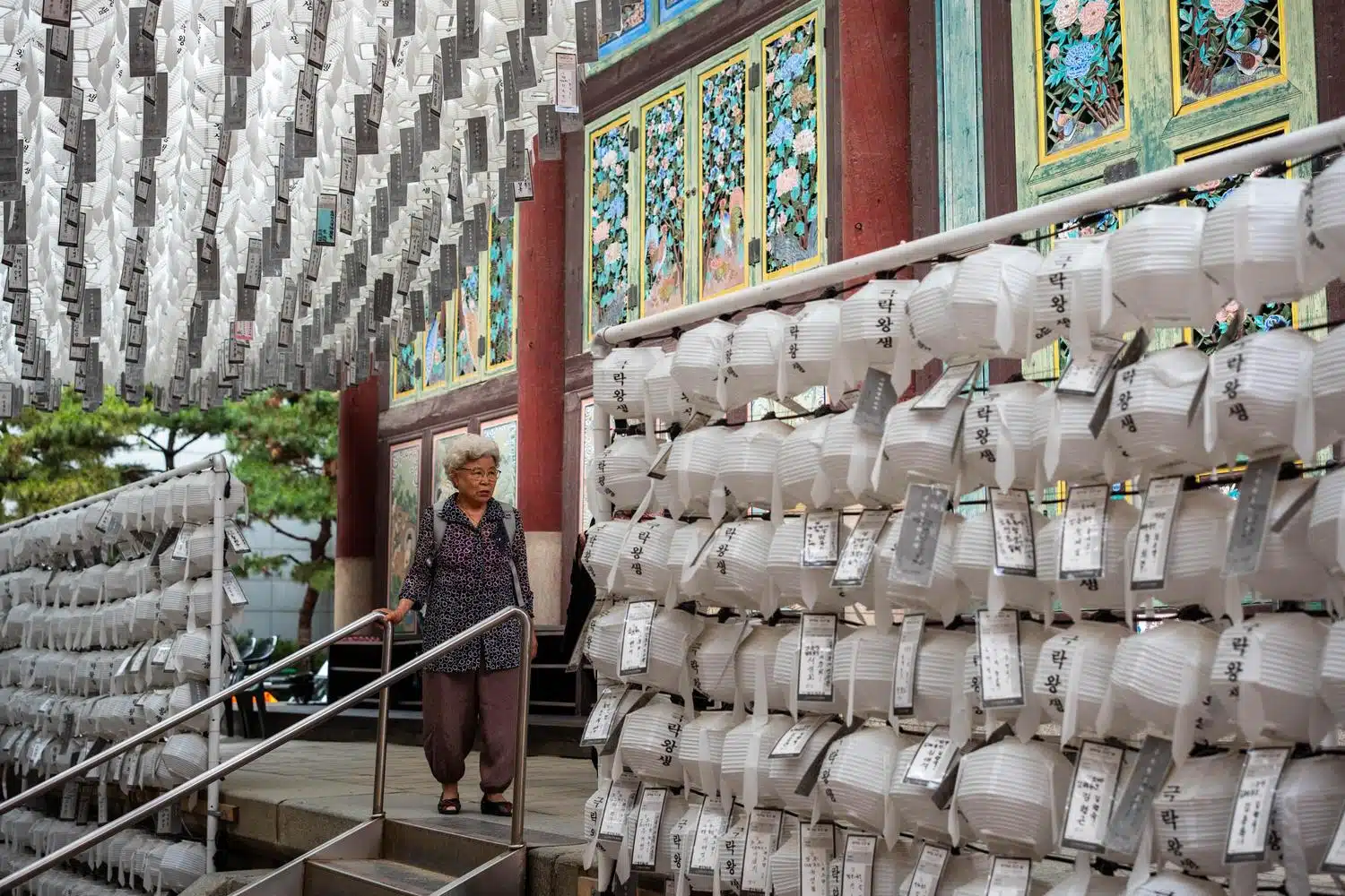 jogyesa-seoul-white-lanterns-2026-06 An elderly lady stands next to white lanterns at Jogyesa buddhist temple in Seoul.