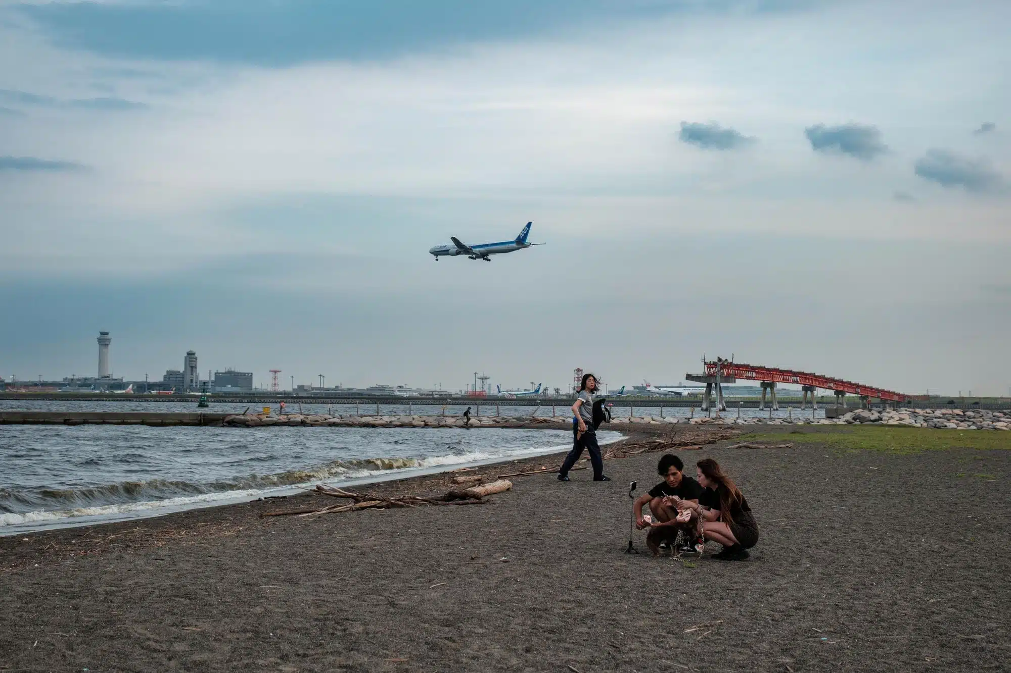 tokyo-haneda-airport-2026-8 People relax on a beach next to Tokyo Haneda Airport.